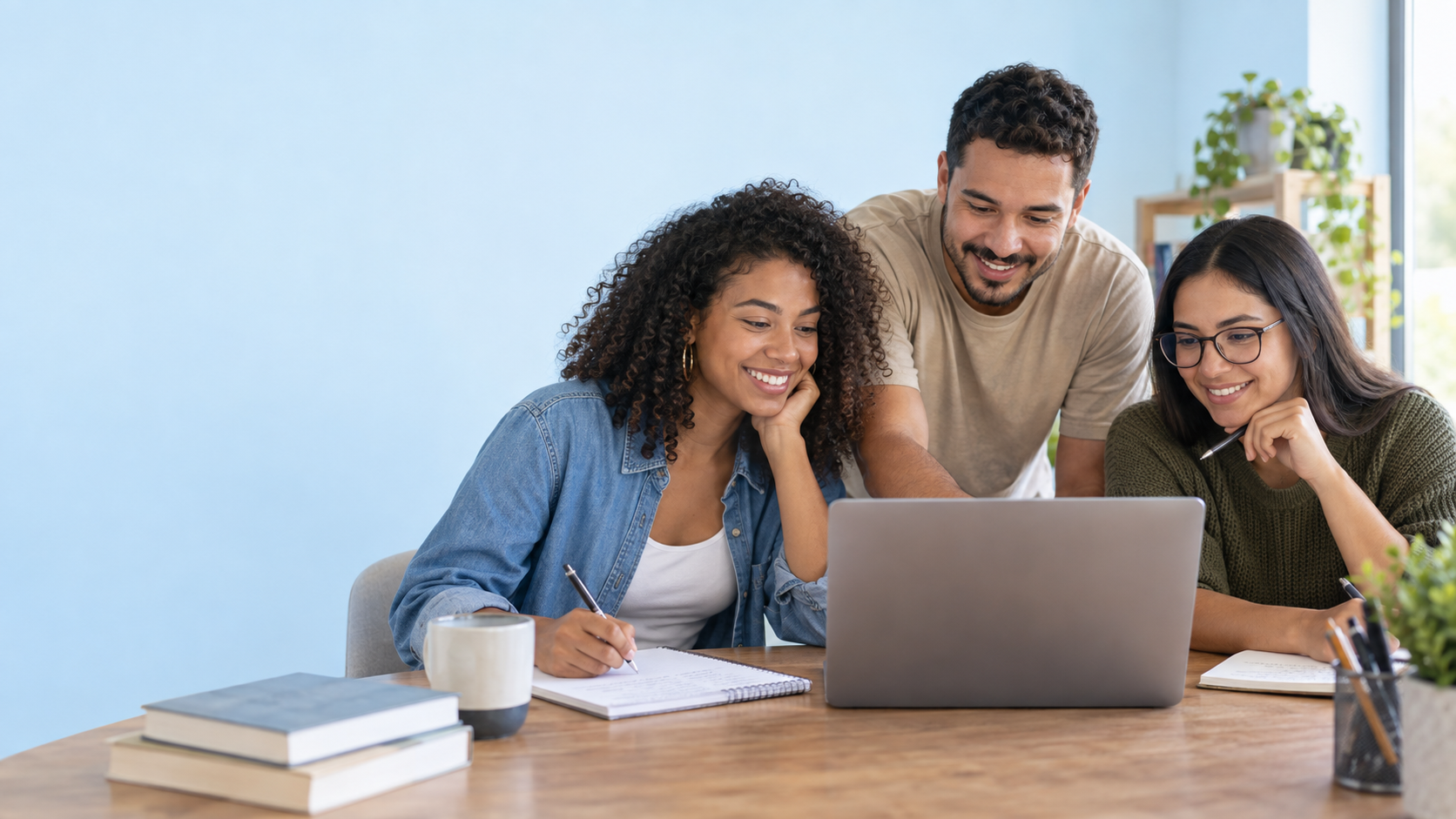 Três estudantes estudando juntos com cadernos e computador